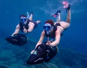 Two snorkelers using Skylork sea scooters above the rocky seabed