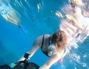A snorkeler using a sea scooter above submerged wreckage