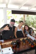 Three guests posing behind the Academy of Rum blending counter