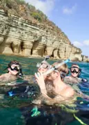 Snorkeling guests at the surface beside coastal rock formations