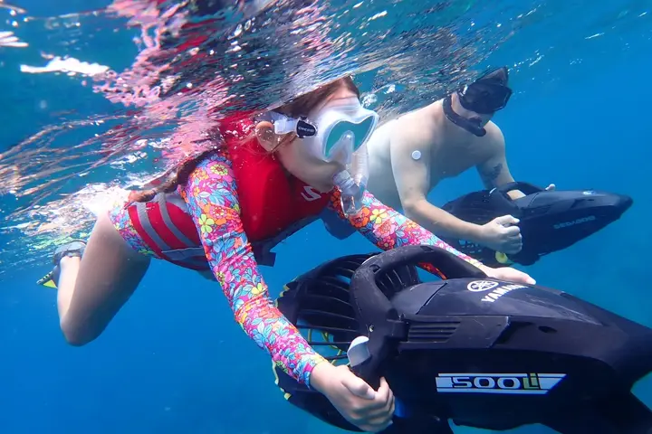 Two guests snorkeling side by side with powered sea scooters