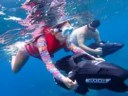Two guests snorkeling side by side with powered sea scooters